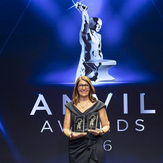An Anvil Award attendee with two Awards of Excellence