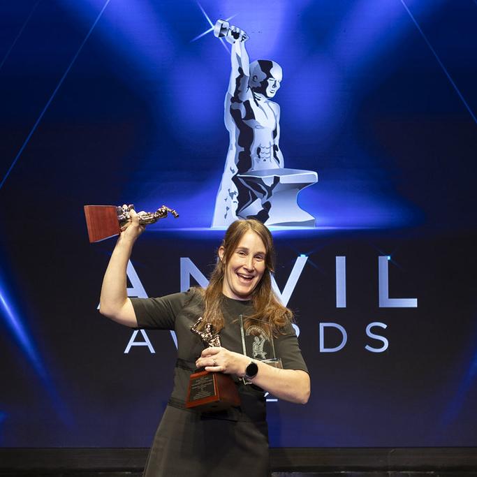 Anvil award winner on stage holding two trophies
