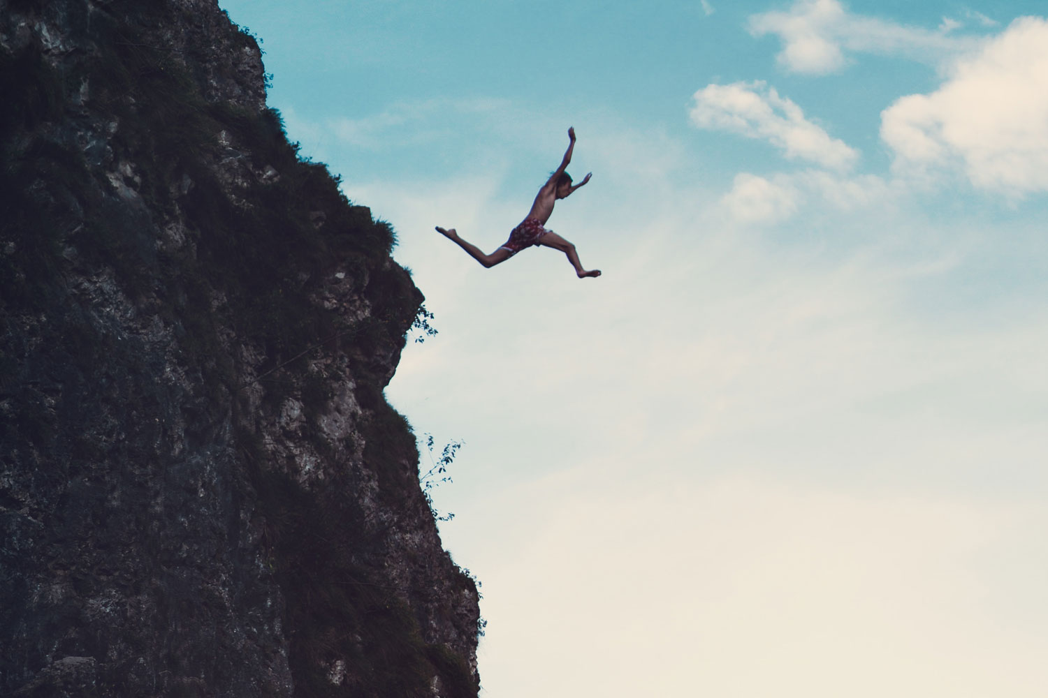 person leaping off mountain