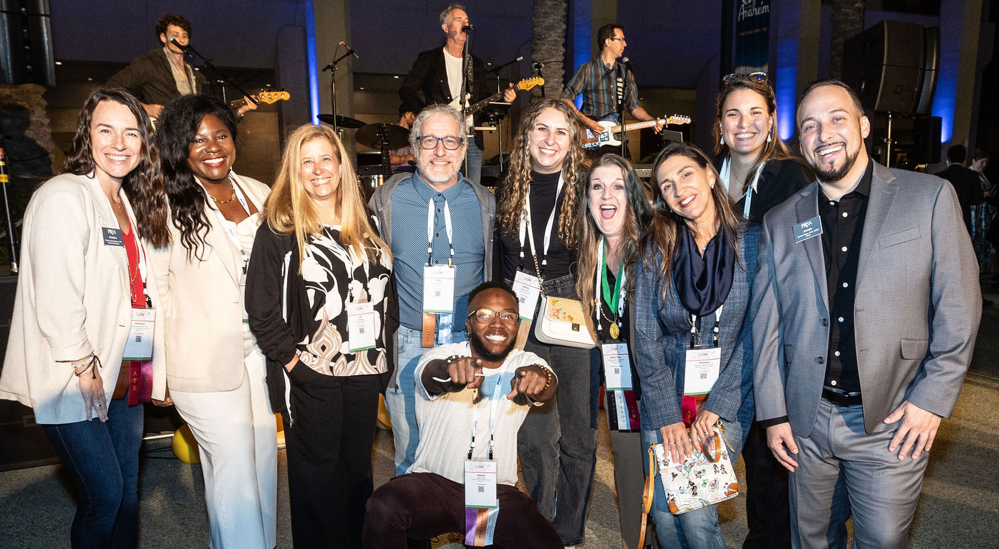 PRSA attendees group shot in front of rock band on stage