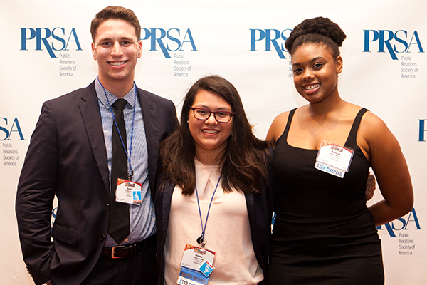 Group Members 2 Three PRSA members smiling at the camera standing infront of a PRSA step-and-repeat. They are dressed in business and formal attire.