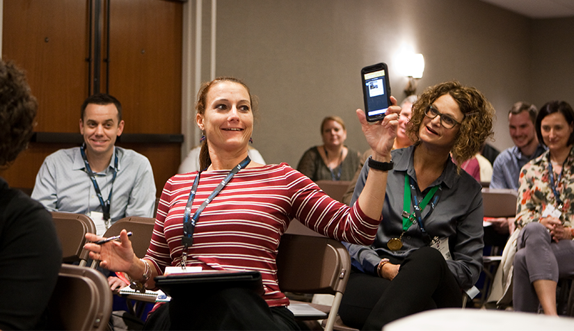 Group Members A PRSA member holding up her phone in a learning session at a conference as part of a demonstration.