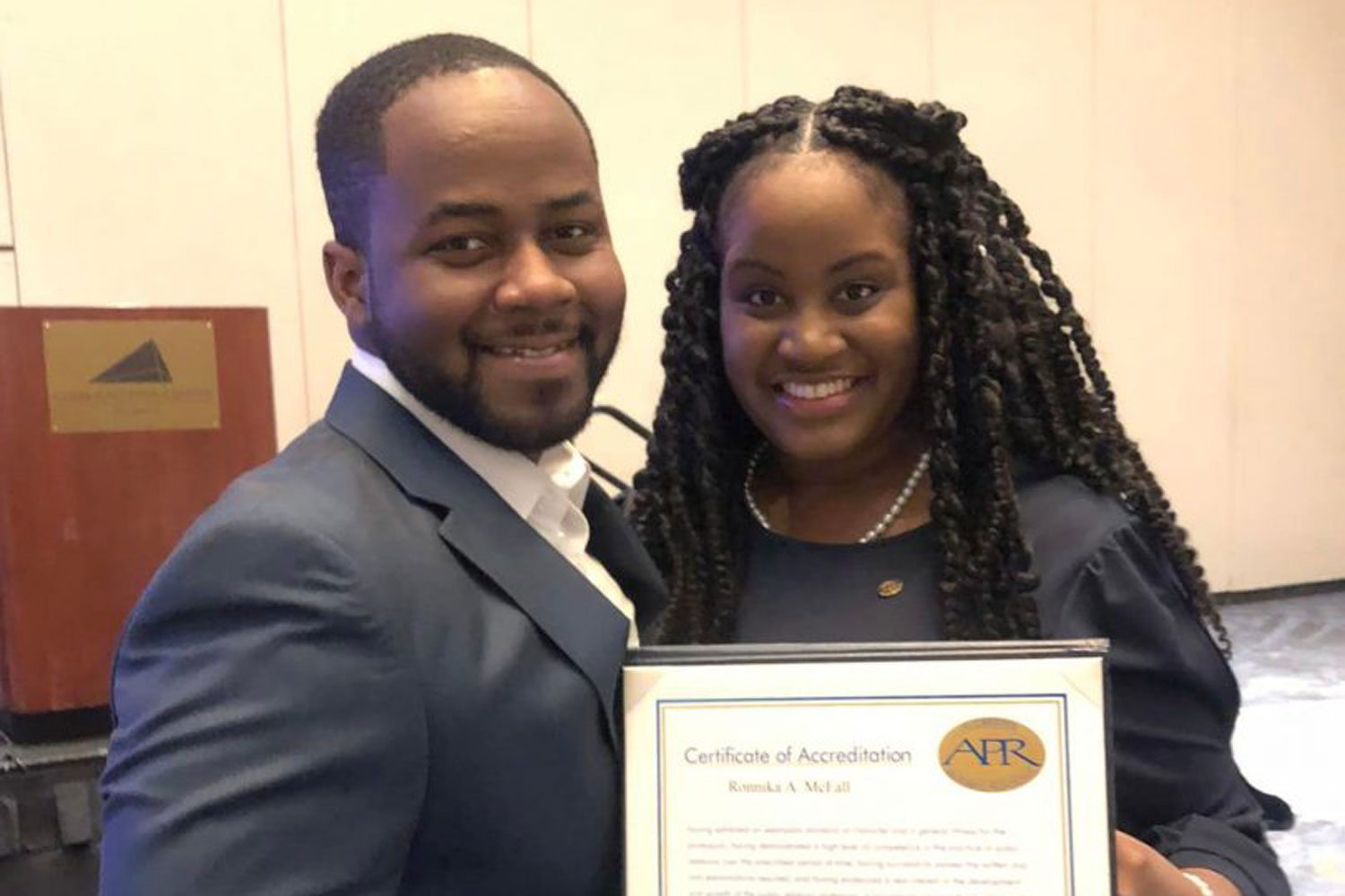 two young adults holding a certificate