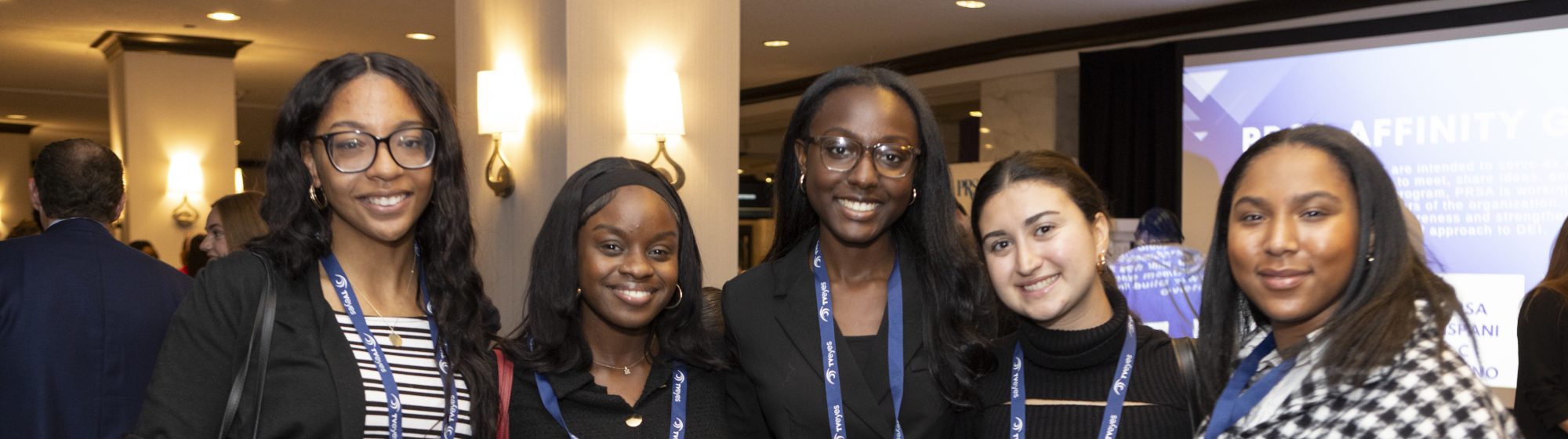 Seven PRSSA students in front of logo backdrop