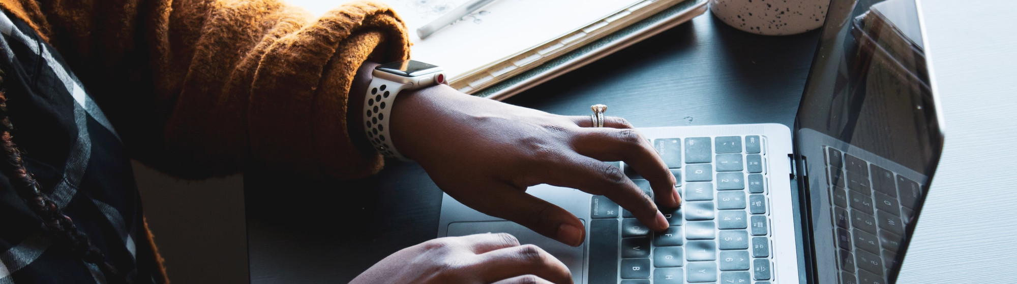 Person typing on a laptop next to a window