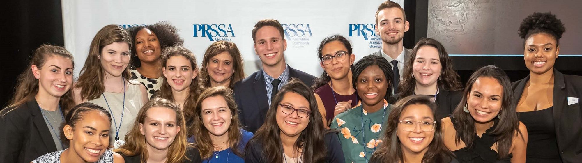Large group of students in front of PRSSA logo backdrop